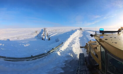 Grader plowing snow drift at Pipeline Crossing - Dalton Highway; North Slope Haul Road, Alaska