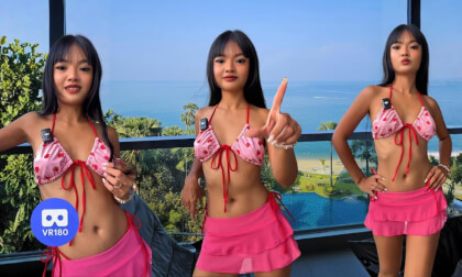 Lilly making TikToks on a balcony with a beautiful seaside view.