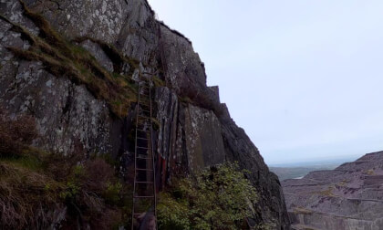 Clambering up 100 year old ladders in the Dinorwic slate quarry, North Wales, UK