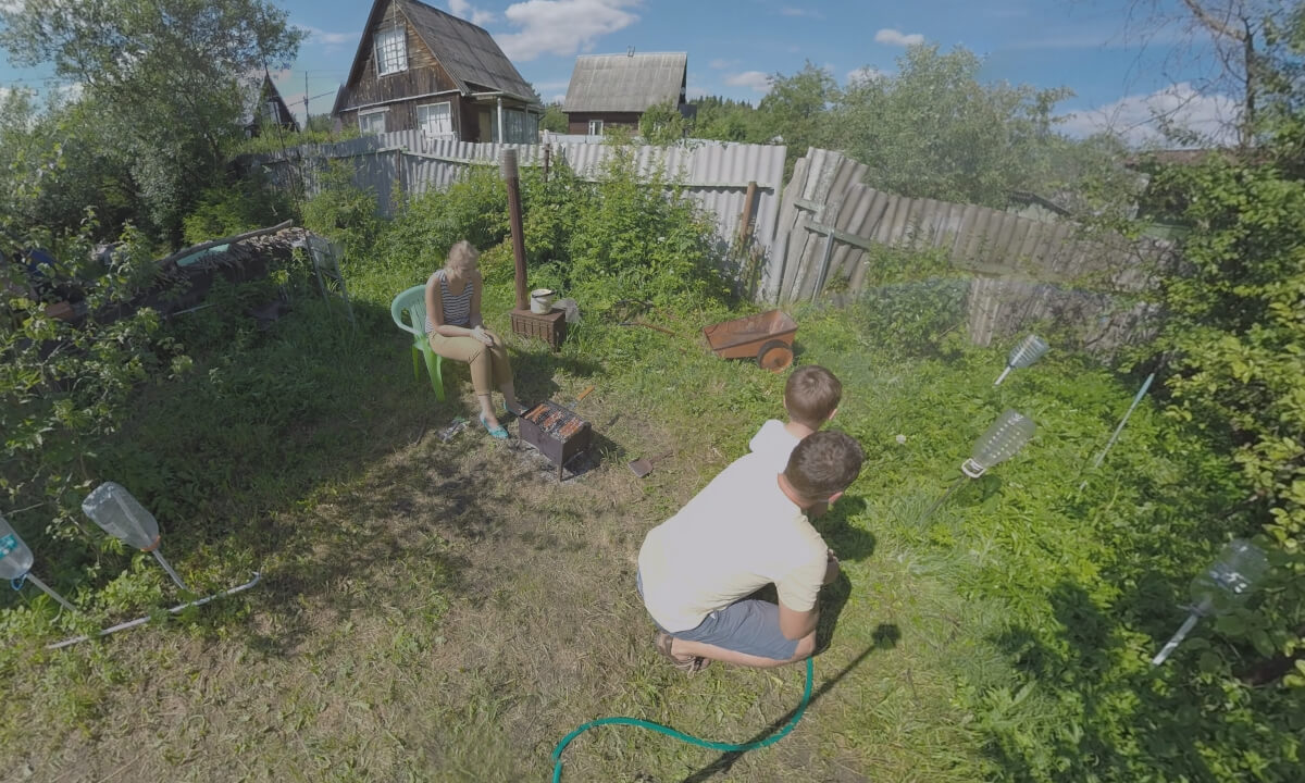 360 VR Parents with children making barbecue and watering plants in the yard of country house