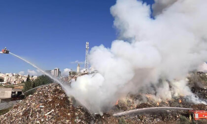 A hill of junk made of car parts, metal and wood is burning. Water cannons shoot at the fire at 100 liters per second.